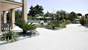 A spacious outdoor area with a pool, seating, and various plants.