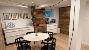 Cocina moderna con encimera blanca, sillas negras y paneles de madera.