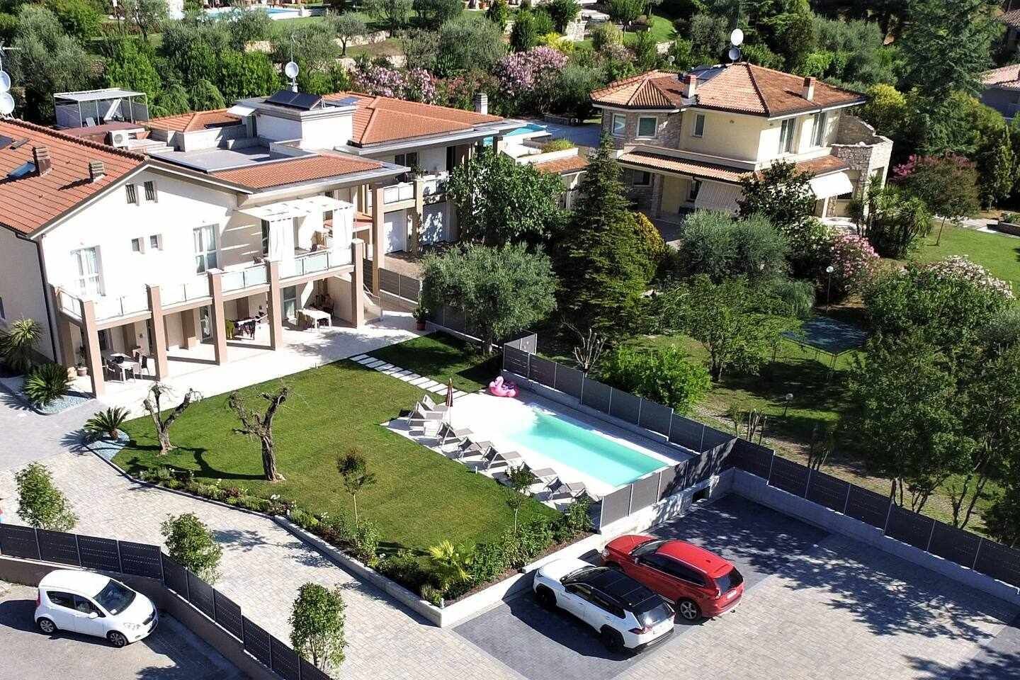 Um imóvel residencial com piscina, varanda coberta e entrada para carros.