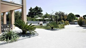 Ampla área externa com piscina, assentos e diversas plantas.