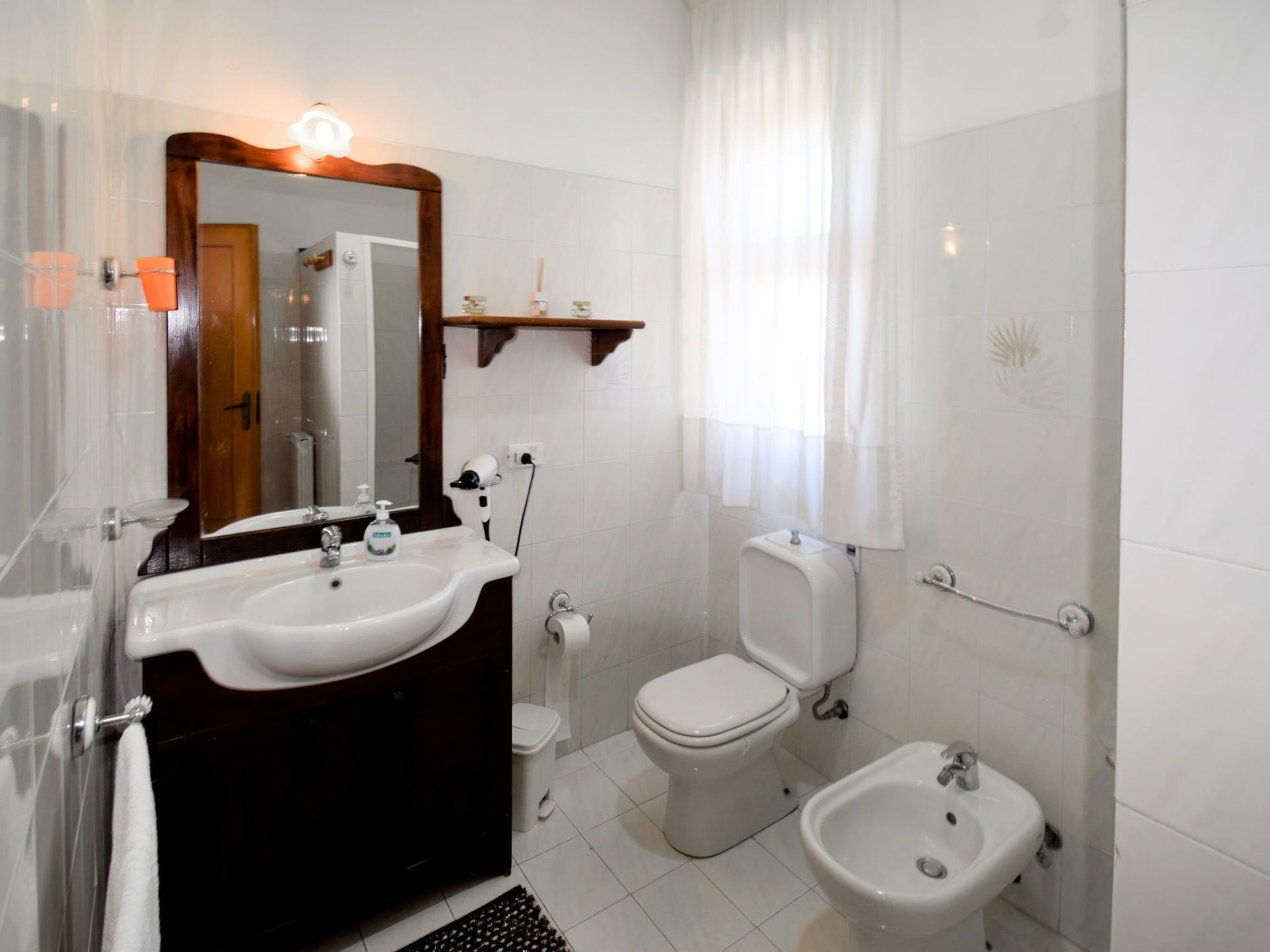 Ein Badezimmer mit einem weißen Waschbecken, einem Spiegel, einer Toilette, einem Bidet und einer Duschkabine.