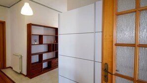 A room with a wooden bookshelf, a radiator, a white wardrobe, and a door with frosted glass panels. - Nice apartment for 6 guests with WIFI, A/C, TV, terrace and pets allowed (Santa Venerina)