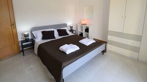 A bedroom with a bed, bedside tables, a wardrobe, and a nightstand with a lamp. - Nice apartment for 6 guests with WIFI, A/C, TV, terrace and pets allowed (Santa Venerina)