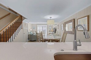 A modern kitchen with a central island, a stainless steel faucet, and a dining area with a round table and chairs.