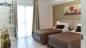 Habitación de hotel con dos camas, un cuadro en la pared, una planta en maceta y una ventana con cortinas.