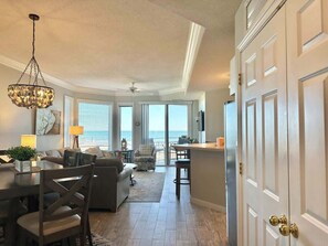 A spacious living area with a dining table, sofas, and a view of the ocean.