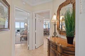 Stunning hallway leads to a dining area with a large mirror, floor lamp, and potted plant.
