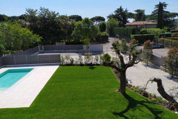 Il s’agit d’une propriété résidentielle dotée d’une piscine, d’une pelouse bien entretenue et d’une variété d’arbres et d’arbustes.
