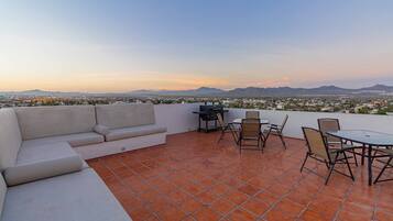 Una terraza en la azotea con sofá, sillas y una mesa.