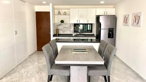 Una cocina moderna con armarios blancos, salpicadero de mármol y horno empotrado.