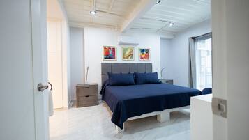 A modern bedroom with a bed, bedside tables, and artwork on the wall.