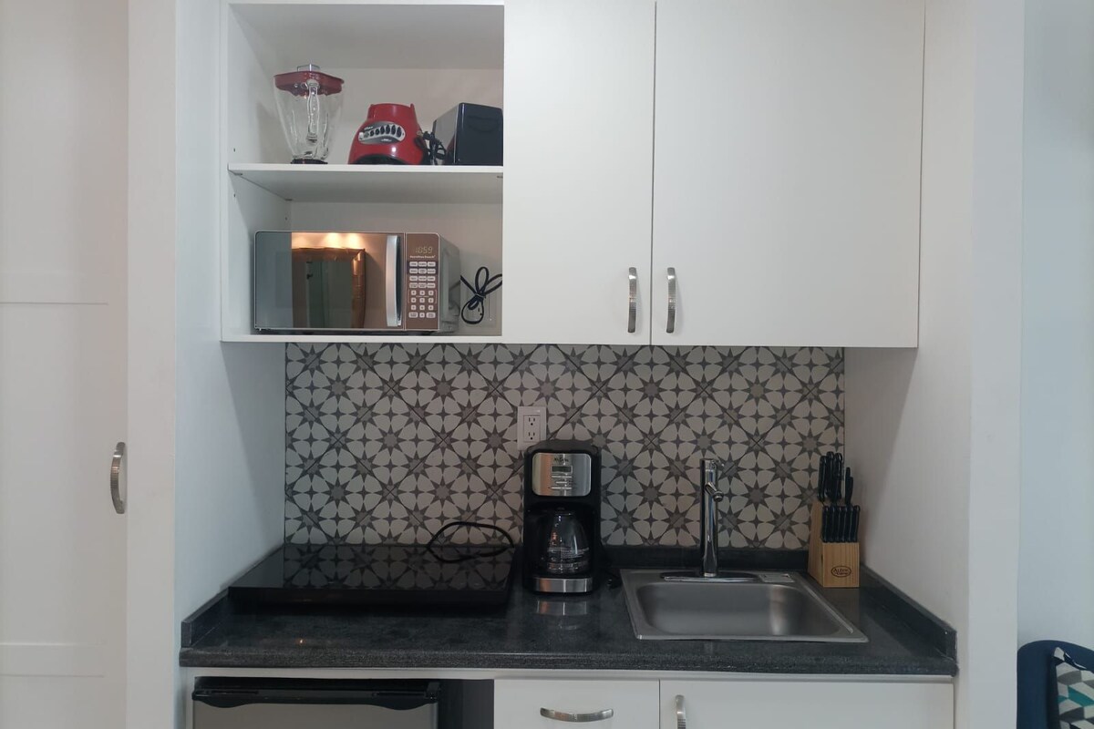 A kitchen with white cabinets, a microwave, a coffee maker, and a sink.