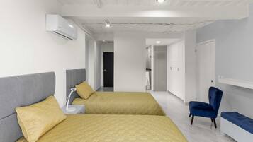 A modern hotel room with two beds, a desk, a chair, and a wardrobe.
