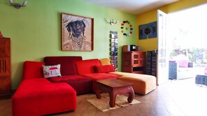Ein Wohnzimmer mit einem roten Sofa, einem Holzschrank und einem Bild an der Wand.