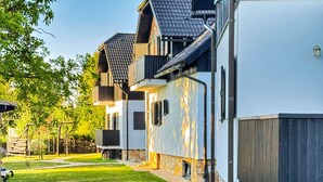 Un immeuble résidentiel doté d’un chemin en pierre, d’une terrasse en bois et d’une pelouse bien entretenue.