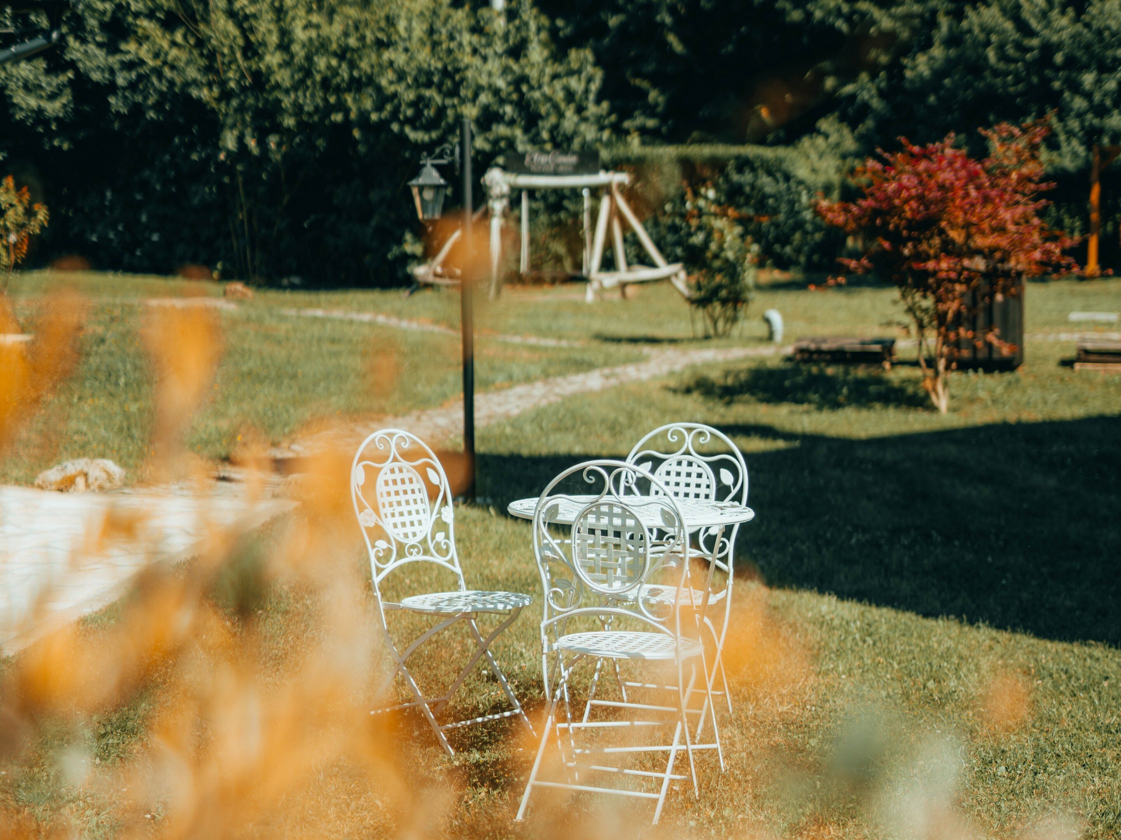 A garden with metal chairs and a swing set.