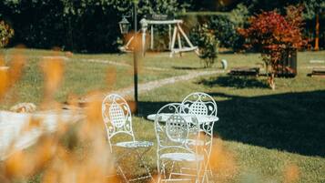 A garden with metal chairs and a swing set.