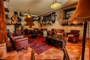 A cozy lounge area with leather sofas, a red patterned rug, and a stone wall backdrop. - Traditional house in Plitvice lakes (Plitvice lakes)