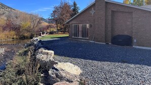 A brick building with a garage, a gravel driveway, and a river in the background.