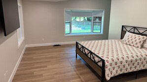 A bedroom with a bed, a window, and a TV mounted on the wall.