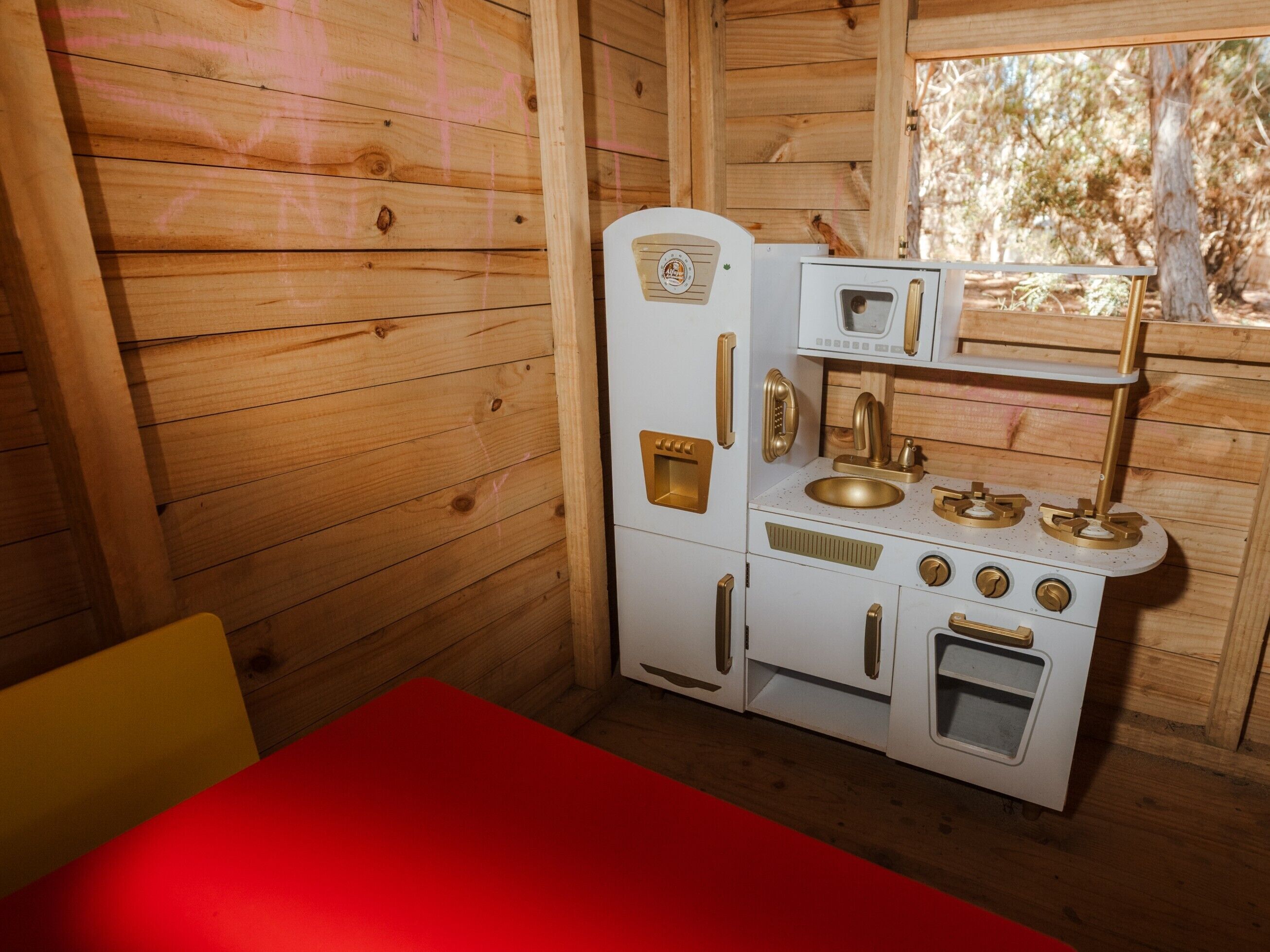 Cocina compacta con microondas, estufa y lavamanos, todo en estilo de cabaña de madera.
