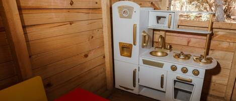 A compact kitchen with a microwave, stove, and sink, all in a wooden cabin style.