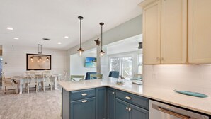 Une cuisine moderne avec des meubles bleu foncé, un plan de travail blanc et des luminaires suspendus.