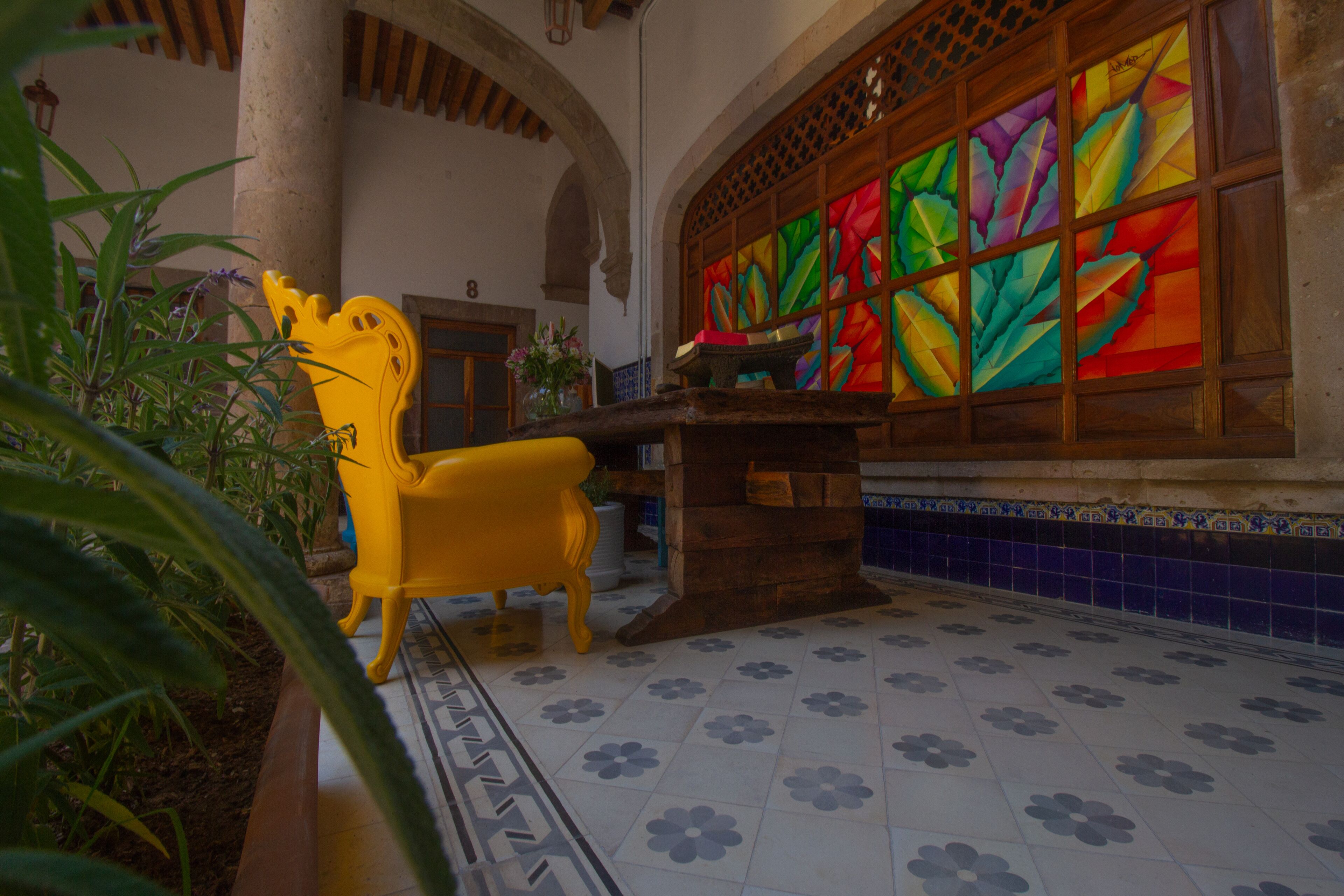 A room with a tiled floor, a wooden bench, and a colorful stained glass window.