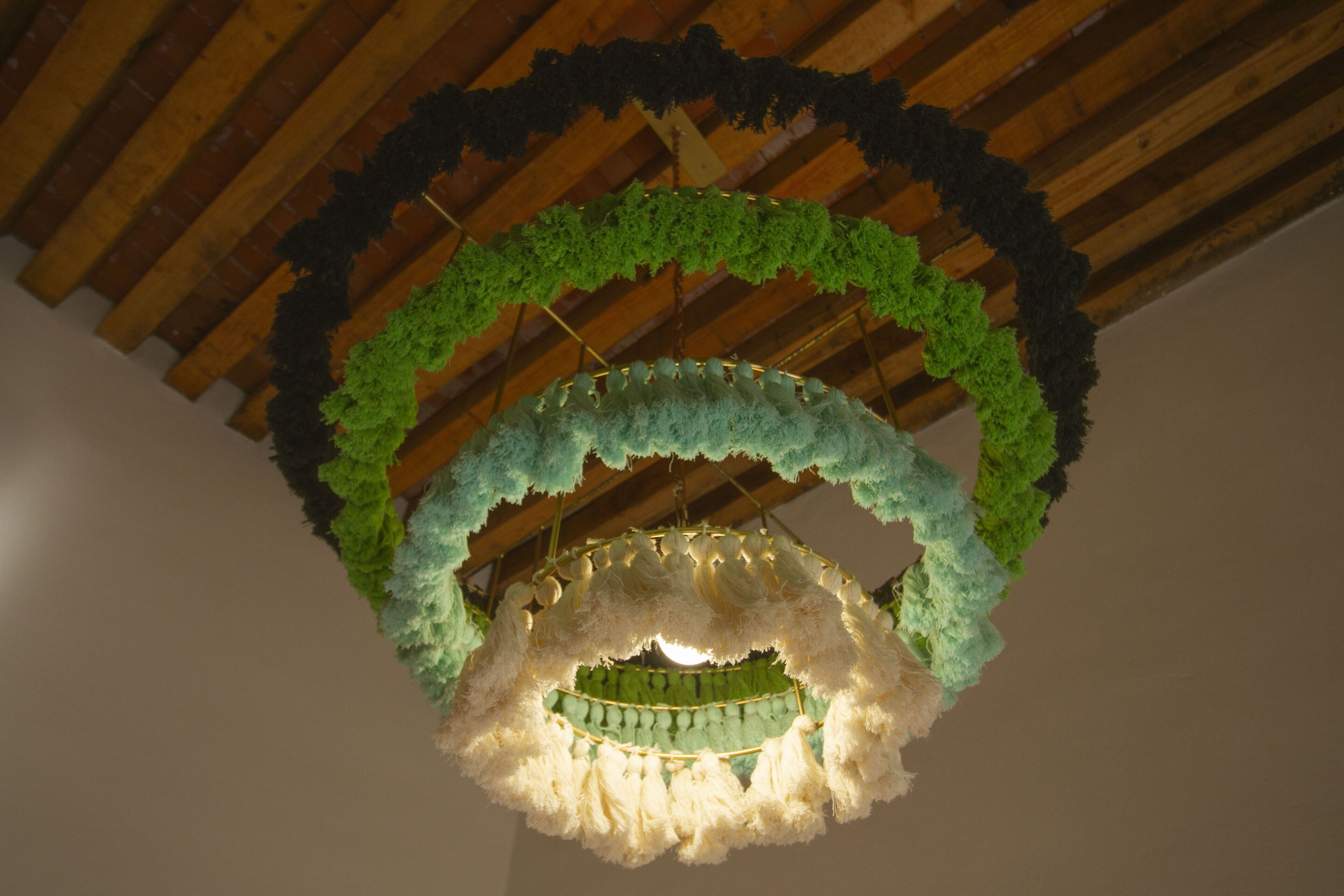 A chandelier with a green and white color scheme, suspended from a wooden ceiling with exposed beams.