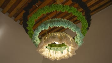 A chandelier with a green and white color scheme, suspended from a wooden ceiling with exposed beams.