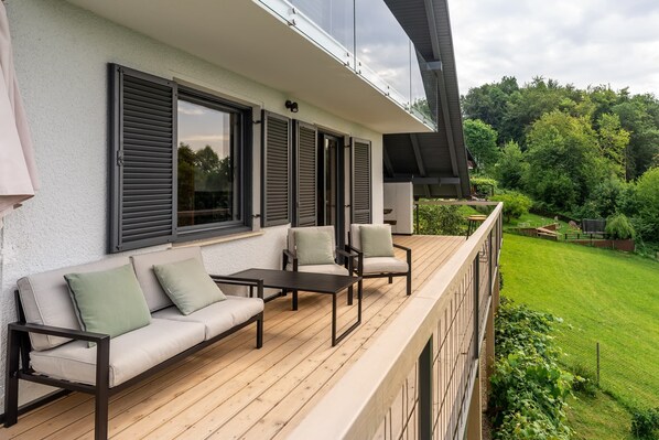 A balcony with a sofa, chairs, and a table.