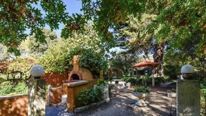 A rustic outdoor area with a brick oven, stone benches, and a red umbrella. - Idyllic Tuscan Paradise with Magical Gardens (Tantanoola)