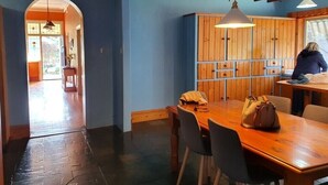 A dining area with a wooden table and chairs, a hanging light fixture, and a wooden cabinet with a window. - Idyllic Tuscan Paradise with Magical Gardens (Tantanoola)