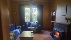 A cozy living room with a fireplace, a sofa, a coffee table, and a view of the outdoors through large windows. - Idyllic Tuscan Paradise with Magical Gardens (Tantanoola)