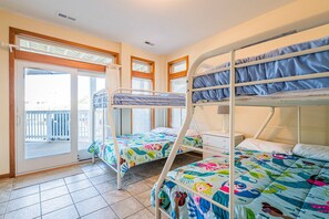 A room with two bunk beds, a window with blinds, a door, and a tiled floor. - Summer Winds - Corolla, Whalehead, 300 Yds to Beach, Elevator, Pool, Hot Tub, Pets OK (Corolla)