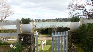 Un portail en pierre qui mène à un sentier offrant une vue sur un lac et des maisons situées au loin.