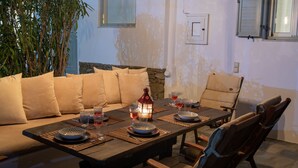 A dining area with a long table set for four, surrounded by cushioned seating. - Drafies House (Mykonos)