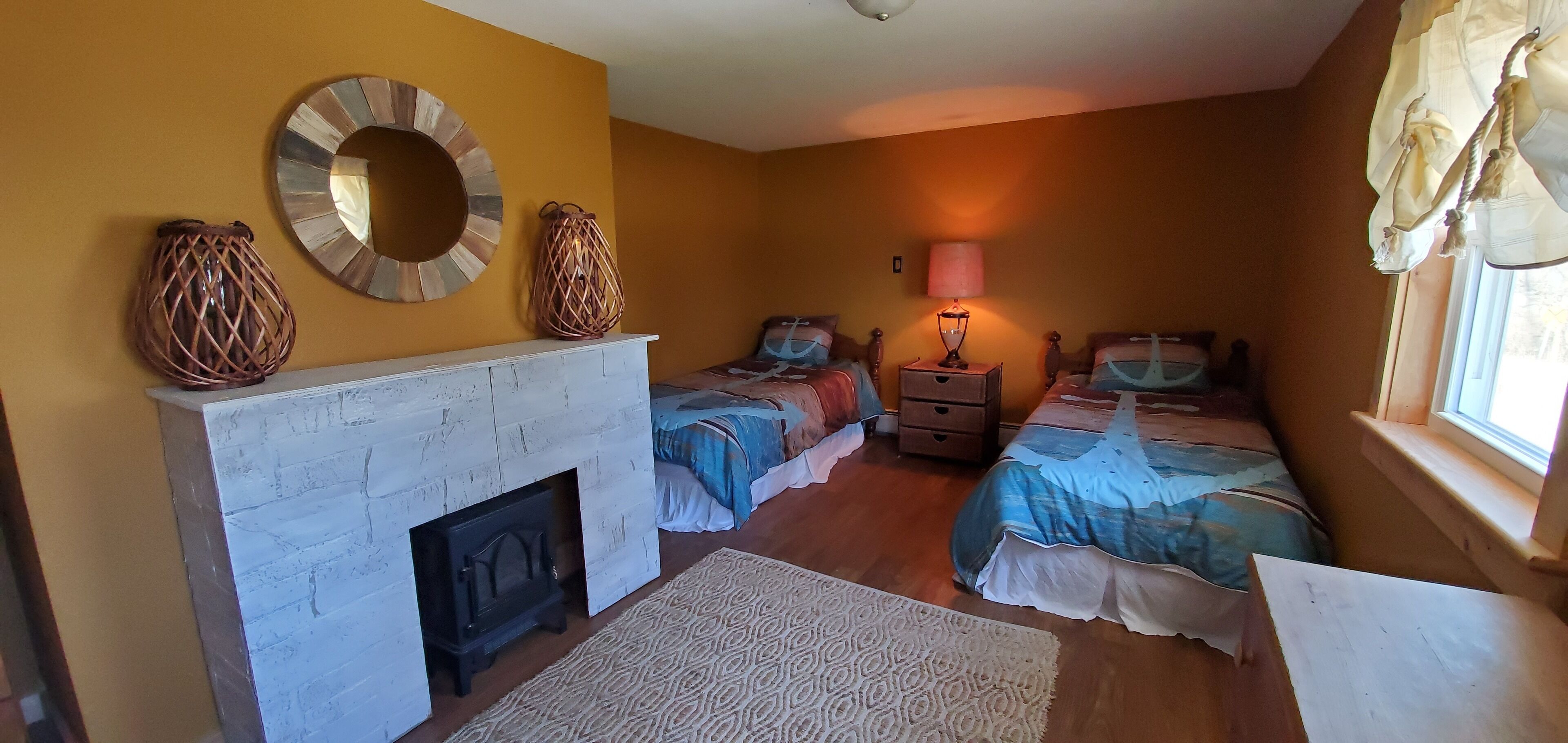 A room with two beds, a fireplace, and a window with curtains.