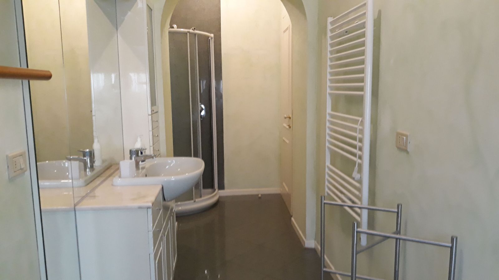 Un baño moderno con ducha de vidrio, lavamanos y perchero para toallas.