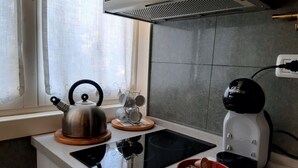 A kitchen with a kettle, a coffee maker, and a bowl on the counter.