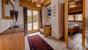 A cozy room with a wooden ceiling, a bed, a chair, a desk, and a large window. - Chalet Coeur - Jacuzzi - Sauna - Views - La Tzoumaz, 4 Vallees (La Tzoumaz)