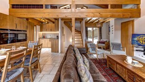 A spacious living area with a high ceiling, wooden beams, a large sofa, dining table, and chairs. - Chalet Coeur - Jacuzzi - Sauna - Views - La Tzoumaz, 4 Vallees (La Tzoumaz)