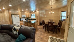 Un intérieur de chalet chaleureux comprenant un salon, une cuisine et un coin repas.