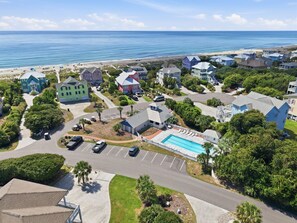 Ett bostadsområde med en swimmingpool, hus och en strand i bakgrunden.
