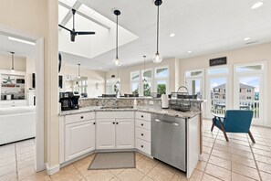 A modern kitchen with a built-in dishwasher, a large island with a sink, and pendant lighting.