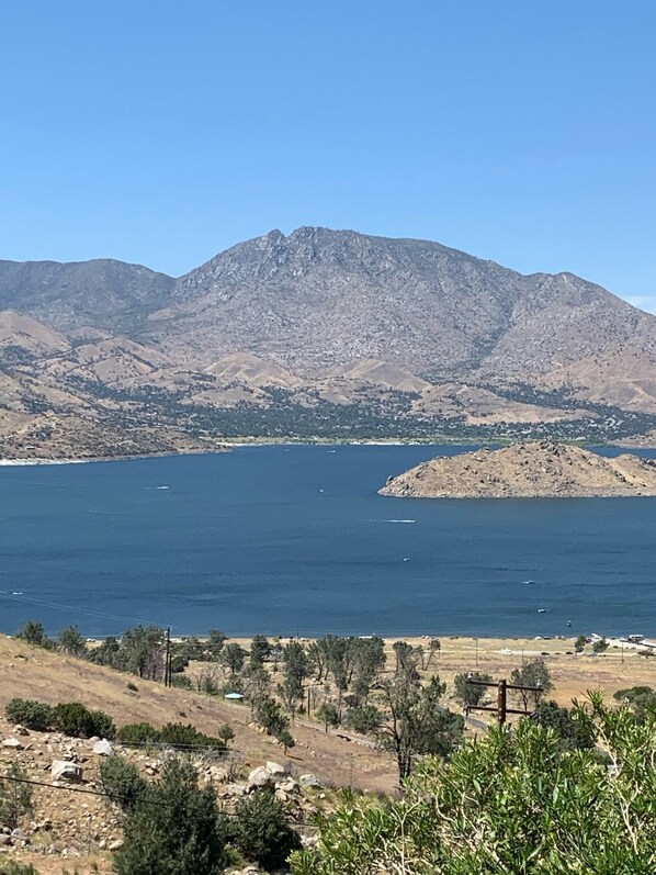 A mountainous landscape with a clear blue lake, rocky terrain, sparse vegetation, and a few boats on the water. - Lake View and close to Beach (LAKE ISABELLA)