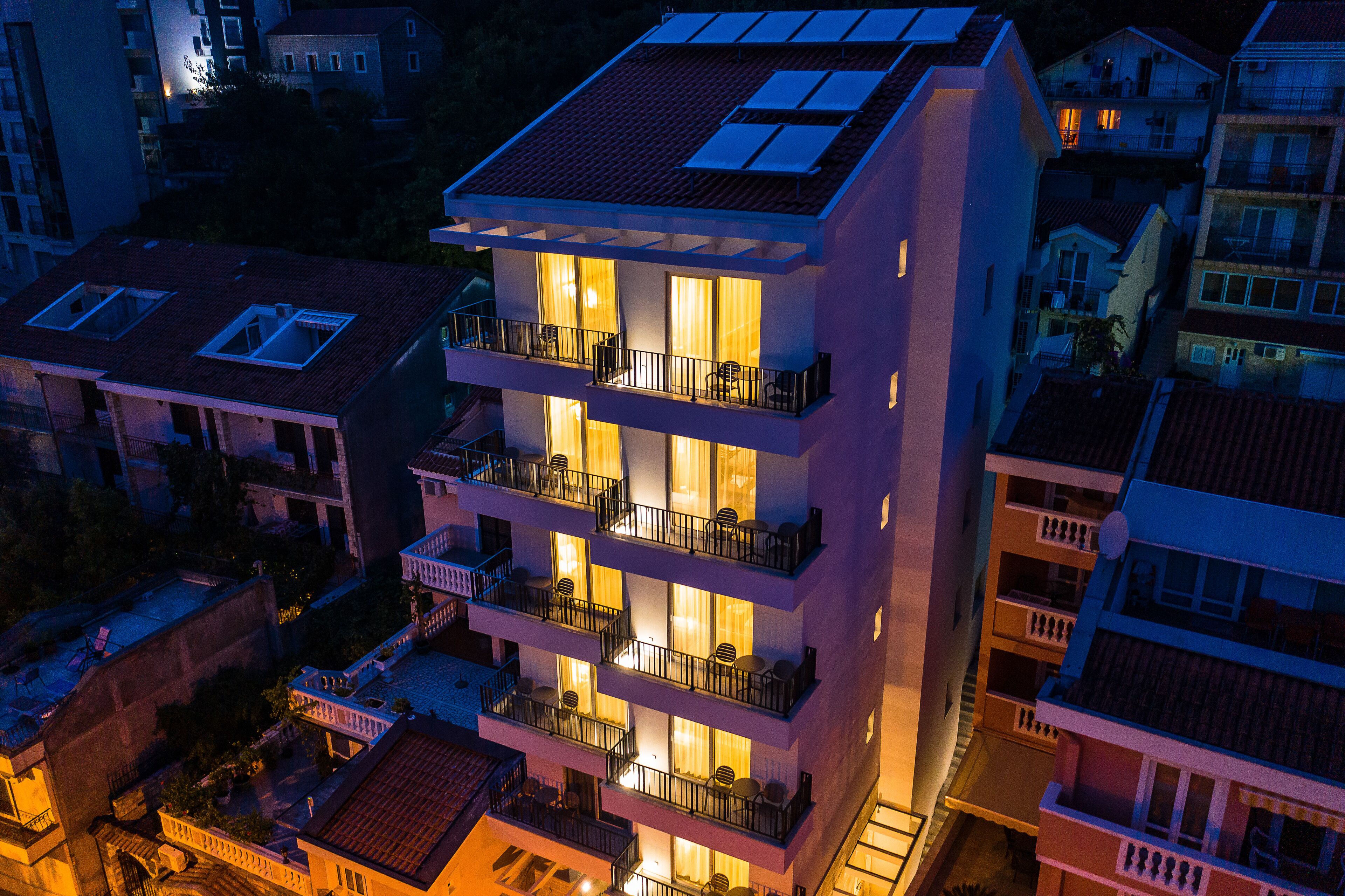 Un edificio de varios pisos con balcones y ventanas amplias, rodeado de otros inmuebles.