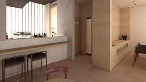 A modern kitchen with a bar area, wooden bar stools, and a dining table with chairs. - Hotel Bono (Becici)