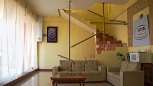 Un hall d’hôtel avec un escalier, un canapé, un fauteuil et une table.