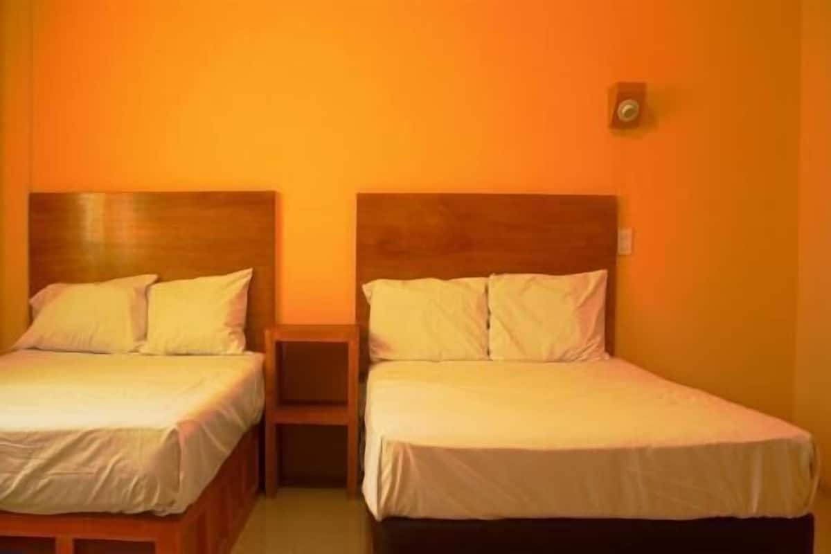 Zwei Einzelbetten mit Holz Kopfteilen in einem Zimmer mit orangefarbenen Wänden.